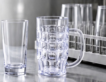 Reusable tumbler and handled mug beside a commercial dishwasher